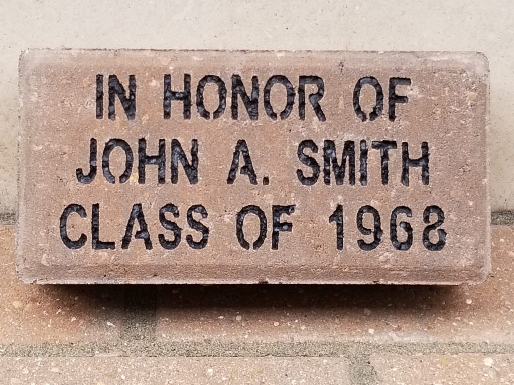 A brick with "In Honor of John A. Smith Class of 1968" engraved.